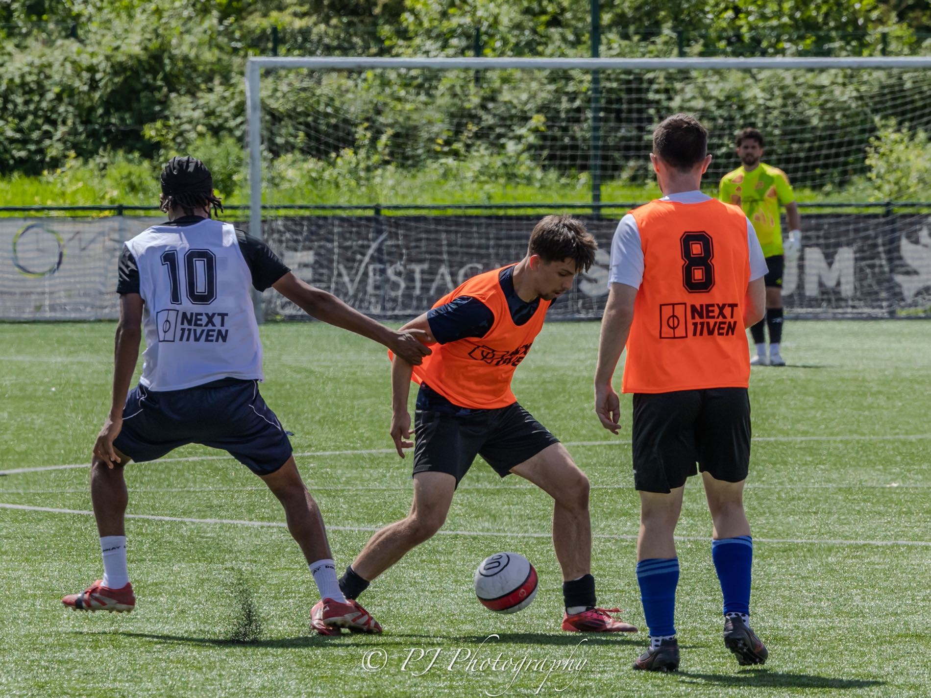 Players in NEXT11VEN bibs competing for the ball during a trial day match.